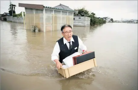  ?? Picture: REUTERS ?? DISASTER: A man holding a box of his belongings wades through a road in a suburb flooded by the Omoigawa River, caused by typhoon Etau in Oyama, Tochigi prefecture, Japan. Officials issued warnings of “once in a half century rains” to 5 million people...
