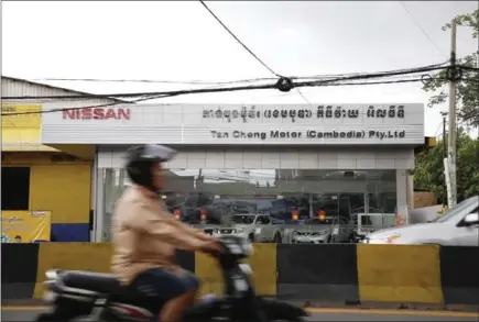  ?? HONG MENEA ?? Traffic passes in front of a Nissan dealership in Phnom Penh yesterday.