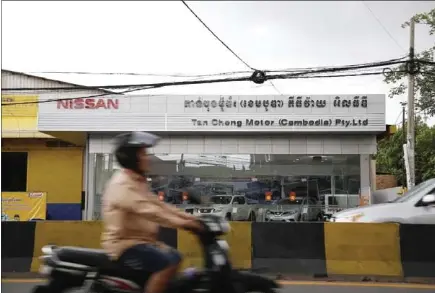  ?? HONG MENEA ?? Traffic passes in front of a Nissan dealership in Phnom Penh yesterday.