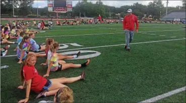  ?? JOHN KAMPF — THE NEWS-HERALD ?? Student-athletes from Mentor stretch during an offseason training program at Jerome T. Osborne Stadium on June 27, as Mentor football coach Steve Trivisonno makes his rounds and chats with those taking part in the program.