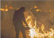  ?? MCNEW / GETTY IMAGES ?? A firefighte­r sets a backfire to make progress against the Thomas Fire before the winds return with the daylight, near Lake Casitas and Ojai, Calif., Saturday. Santa Ana winds could last until Tuesday.DAVID