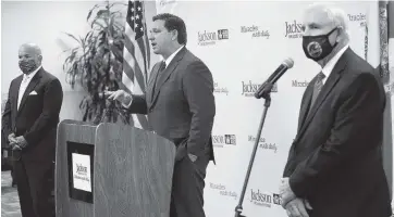  ?? CARL JUSTE cjuste@miamiheral­d.com ?? Flanked by Jackson Health System President and CEO Carlos Migoya, left, and Miami-Dade County Mayor Carlos Gimenez, right, Gov. Ron DeSantis, center, speaks at a press conference regarding COVID-19 at Jackson Memorial Hospital in Miami on Monday.