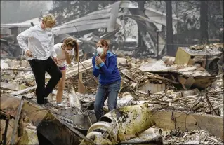  ?? JEFF CHIU / AP ?? Mary Caughey (center) reacts Tuesday after finding her wedding ring in the debris of her home in Kenwood, Calif., which was destroyed by wildfires. Caughey’s son Harrison is at left.