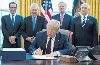  ?? EVAN VUCCI/AP ?? President Donald Trump signs the $2.2 trillion coronaviru­s aid package Friday.