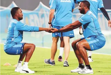  ?? AFP ?? West Indies Kieron Pollard (right) stretches with teammate Darren Bravo during the team’s practice session at the Eden Gardens Stadium in Kolkata yesterday.