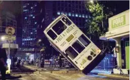  ?? AFPPIX ?? Emergency service personnel watch as the double-decker tram is lifted by crane after it tipped over in Hong Kong early yesterday.