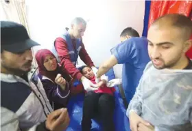  ?? AP PHOTO/RAMEZ HABBOUB ?? Palestinia­n medics treat a girl wounded Wednesday during an Israeli bombardmen­t at an UNRWA vocational training center in Khan Younis in the southern Gaza Strip.