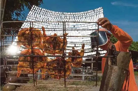  ?? AFP PIC ?? Food vendor Sila Sutharat cooking chicken with rays of sun reflected on an oversized mirror panel in Petchaburi province, south of Bangkok, recently.