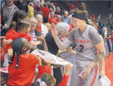 ?? GREG SORBER/JOURNAL ?? New Mexico’s Tesha Buck high-fives young fans after the Lobos beat Rice in the second round of the WNIT on Tuesday night in the Pit. Buck got her 100th 3-pointer of the season in UNM’s victory.