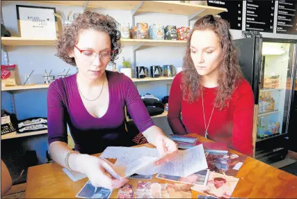  ?? SUZANNE TENNANT/POST-TRIBUNE ?? Sisters, Leanna Hall, 26, left, and Nadjezda Lof, 23, look over some of the items they have left of their biological history in the Ukraine.