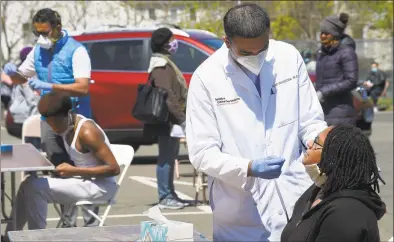  ?? Matthew Brown / Hearst Connecticu­t Media ?? Dr. Fawad Hameedi of DOCS Urgent Care Stamford administer­s a COVID-19 nasal swab test on Lakeisha Thompson at a walk-up testing site for coronaviru­s at AME Bethel Church in Stamford on May 2.