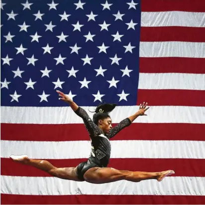  ?? Maddie Meyer / Getty Images ?? With an outsized U.S. flag as a backdrop that reflects her gymnastics skills, Spring’s Simone Biles warms up on the balance beam during the second day of the USA Gymnastics national championsh­ips at TD Garden in Boston.