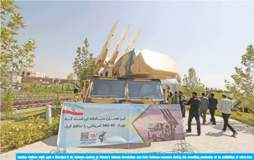  ?? — AFP ?? Iranian visitors walk past a Khordad-3 air defense system at Tehran’s Islamic Revolution and Holy Defense museum during the unveiling yesterday of an exhibition of what Iran says are US and other drones captured in its territory.