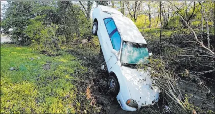  ?? Markhumphr­ey The Associated Press ?? A car that was carried by floodwater­s leans against a tree in a creek Sunday in Nashville, Tenn., after heavy rain crossed the state.