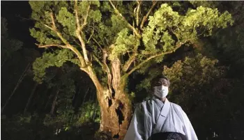  ??  ?? Tetsushi Takeo, a chief priest of Takeo Shrine, poses for a picture in front of an interactiv­e digital installati­on ‘The Sacred Tree’.