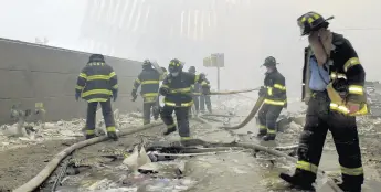  ??  ?? In this Sept. 11, 2001 file photo, firefighte­rs work beneath the destroyed mullions, the vertical struts which once faced the soaring outer walls of the World Trade Center towers, after a terrorist attack on the twin towers in New York. MARK LENNIHAN/AP PHOTO