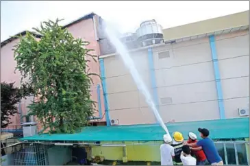  ?? HONG MENEA ?? Firefighte­rs attempt to spray water on a fire in a difficult-to-access part of the Rock Entertainm­ent Centre in Phnom Penh yesterday.