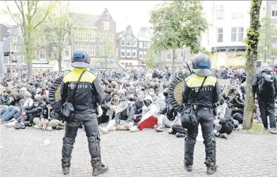  ?? NICK GAMMON/AGENCE FRANCE-PRESSE ?? DUTCH police officers stand in front of Pro-Palestinia­n students of the University of Amsterdam’s Roeterseil­and campus. The students are expressing support to Palestinia­ns in Gaza, in Amsterdam for the fourth night. Some 32 people were arrested by the police for ‘violence, destructio­n, assault and incitement’ at the university and on a major thoroughfa­re in the center of the Dutch capital.