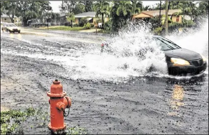  ?? GREG LOVETT / THE PALM BEACH POST ?? A car drives through a flooded Seacrest Boulevard in Boynton Beach on Tuesday, as storms dumped more than 5 inches of rain in parts of Palm Beach County. More is expected today.