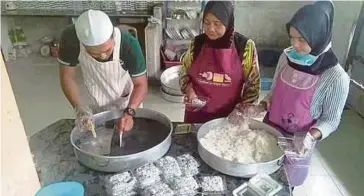  ??  ?? AMIR Yusof memotong kuih kerbau guling sebelum dipek untuk dijual pada harga RM2 satu.