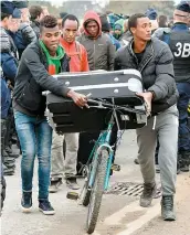  ??  ?? Des réfugiés transporte­nt leurs bagages vers l’un des autobus qui doivent les conduire dans un centre d’accueil.