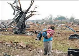  ?? SUE OGROCKI / AP ?? Devastació­n. Una mujer lleva a un niño cerca de la escuela del Plaza Towers, en Moore, Oklahoma