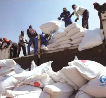  ??  ?? Men offload maize from a food aid agency truck