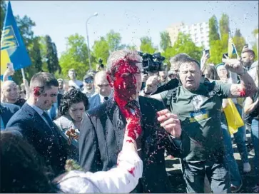  ?? Maciek Luczniewsk­i Associated Press ?? RUSSIA’S ambassador to Poland, Sergey Andreev, is doused with what appears to be red paint after protesters took aim at him as he arrived at a Warsaw cemetery to honor Red Army soldiers who died in WWII.