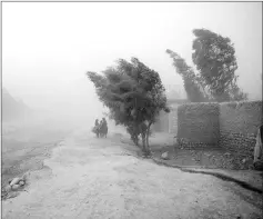  ??  ?? Children make their way home through a violent storm in Afghanista­n’s Nangahar Province. They and their mother, a woman named Shaguftar, fled their home in another district of Nangahar after their father, Mohammad Karim, a chef working for the Afghan...