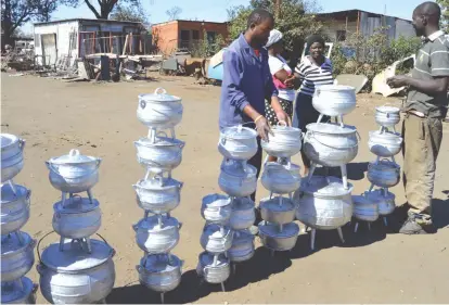  ??  ?? Mr Nelson Nyamutsaga (left) and his colleague Mr Zenzo Ncube negotiate with clients who want to buy three-legged aluminium pots they are manufactur­ing at a makeshift site in Thorngrove industrial sites on Friday. The two men wish to set up a...