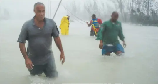  ??  ?? Des volontaire­s marchent sur une route inondée par l’ouragan Dorian alors qu’ils tentent de secourir des habitants près du pont Causarina, à Freeport, Grand Bahama, aux Bahamas. - Associated Press: Ramon Espinoza