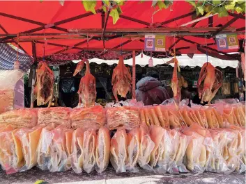  ??  ?? Street vendors sell Sanlin fried pork skins, a local intangible cultural heritage, and fried ducks at their booth.