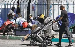  ?? DENIS POROY FOR THE U-T ?? Jarvis Leverson pushes his children Jordan, 11⁄2, and Jetson, 3, past a homeless encampment in downtown San Diego this month.