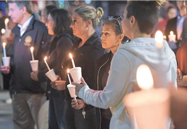  ?? ?? SILENT TRIBUTE: People attend a candleligh­t vigil at Ali Youssefi Square in Sacramento, California, in memory of the victims of the mass shooting.