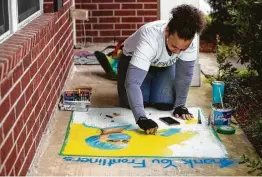  ?? Brett Coomer / Staff photograph­er ?? Lauren Luna, who had been scheduled to teach a class in Baldwin Park, works on a piece of chalk art from her front porch, thanking front-line medical workers.