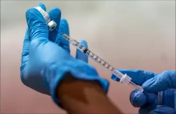  ?? Mary Altaffer/Associated Press ?? Pharmacist Diana Swiga fills a syringe with the Pfizer-BioNTech COVID-19 vaccine Jan. 31 at a vaccinatio­n site in New York. Wrestling with confusing websites has become a stumbling block for many Americans who just want to schedule their shot. So-called vaccine hunters recommend a team effort, various technical tricks and good old-fashioned persistenc­e.