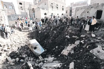  ??  ?? People look at the damage in the aftermath of an air strike in the Yemeni capital of Sanaa on Saturday. AFP PHOTO
