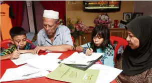  ??  ?? Home school: Ibrahim and azizah helping their grandchild­ren Iqmal daniel Hasrol, 11, and Izzati diyana, nine, with their homework.