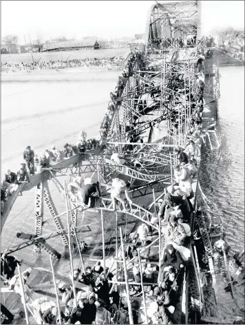  ??  ?? Residents from Pyongyang, North Korea, and other areas crawl perilously over shattered girders of the city’s bridge in December, 1950, as they flee south across the Taedong River to escape the advance of Chinese Communist troops.