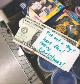  ?? (Courtesy Photo/Debbie McFarland) ?? A dollar bill and encouragin­g note, placed by McFarland, are seen in a bin of toys in a store in Peachtree City.