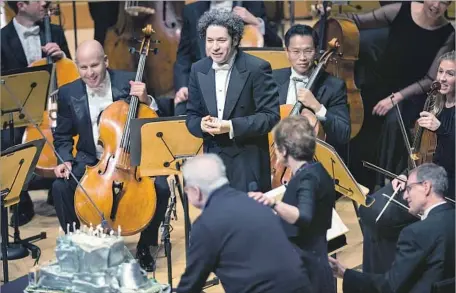  ?? Michael Owen Baker For The Times ?? PIANIST Emanuel Ax, with Deborah Borda, rolls out a cake for Gustavo Dudamel, center. The conductor’s 36th birthday was Thursday.