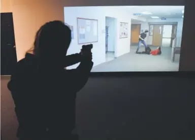  ??  ?? Wheat Ridge police Officer Charlotte Aines goes through a “shoot, don’t shoot” scenario while training with help from a simulator at the Frank DeAngelis Center for Community Safety in Wheat Ridge. Andy Cross, The Denver Post