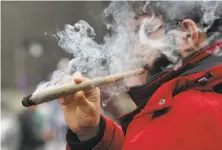  ?? David Kawai / Bloomberg ?? A man indulges in a joint Thursday at a 420 day festival in Ottawa. Canada may soon make recreation­al pot legal.