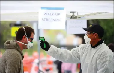  ?? ARIC CRABB — STAFF PHOTOGRAPH­ER ?? A Fremont firefighte­r takes the temperatur­e of a man at a screening station for the COVID-19virus near Hayward Fire Station 7 on Monday in Hayward. The Hayward Fire Department partnered with Avellino Labs to provide 370free tests each day.