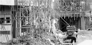  ??  ?? Three North Korean workers (wearing boots) seen working at a constructi­on site along Matang-Batu Kawah Link Road yesterday.