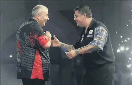  ??  ?? Beaten Gary Anderson congratula­tes Phil Taylor (left) after his dramatic 5-3 defeat in last night’s quarter-final at Alexandra Palace.