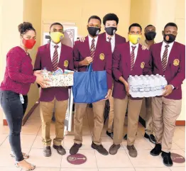  ?? PHOTOGRAPH­ER NICHOLAS NUNES/ ?? Deon Williams (left), Wolmer’s Boys’ School guidance counsellor, receives care packages from Tariq Wright, the president, and other executive members of the club at the school last week.