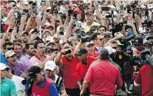  ?? JOHN AMIS/THE ASSOCIATED PRESS ?? Tiger Woods emerges from a horde of fans who rushed the 18th hole in excitement to watch Woods capture his 80th career victory on the PGA Tour, just two short of the record.