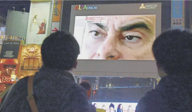  ?? PICTURE: KAZUHIRO NOGI ?? 0 Passers-by look at a screen showing a news programme featuring the arrest and sacking of Nissan chairman Carlos Ghosn in Tokyo