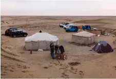  ?? ?? Iraqi campers gather around a fire in the early morning in the Samawa desert south of Baghdad .